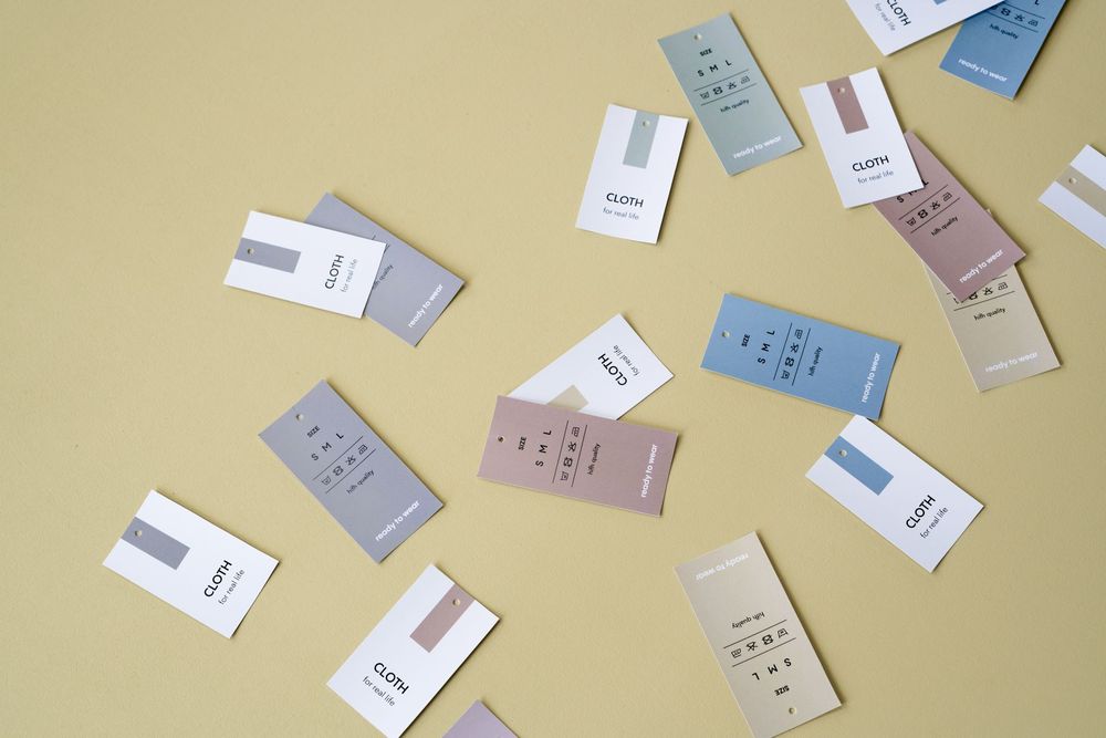 Scattered clothing tags in various colors on a yellow background, perfect for fashion design concepts